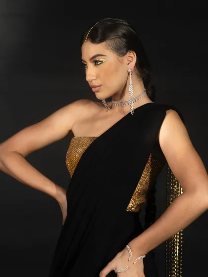 A close-up from the Nikhil Thampi lookbook featuring a black and gold ensemble. The lighting emphasizes the contrast between the two colors and the intricate details of the jewelry.