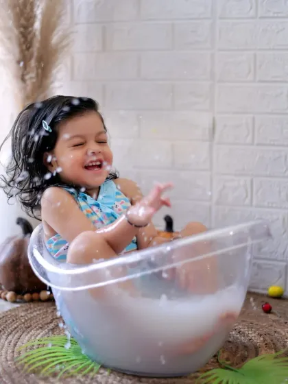 A moment of pure joy as a little girl splashes during her milk bath photoshoot. These sessions are all about fun and capturing genuine laughter.