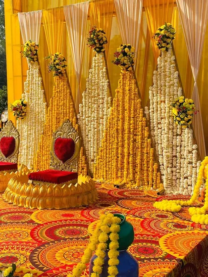 A close-up of the Haldi seating area, with heart-shaped cushions on the chairs and a backdrop of flower cones.