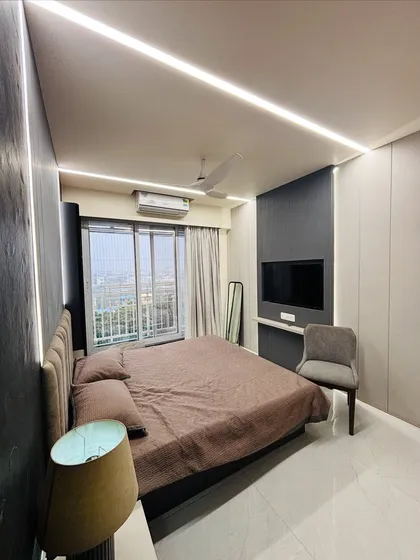 I designed this master bedroom to be a cozy retreat. The combination of dark textured wall panels, soft ambient lighting from the ceiling, and an upholstered headboard creates a warm and inviting modern bedroom.