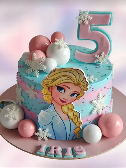 This Elsa-themed cake uses a beautiful blend of pink and blue whipped cream frosting. It's a fun and colorful take on the Frozen theme, decorated with edible snowflakes and chocolate spheres.