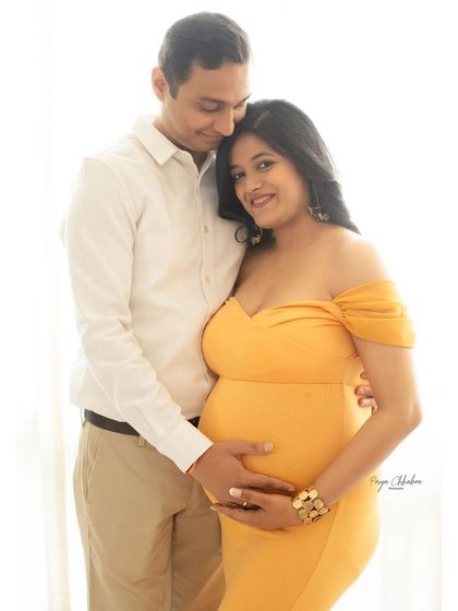 A classic pose for an expecting couple. The partner's hands gently resting on the bump is a timeless way to show their shared love and excitement for the baby.