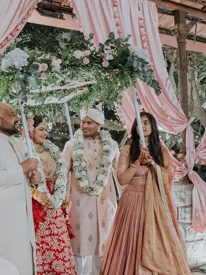The bride and groom's entrance under a floral canopy held by their family.