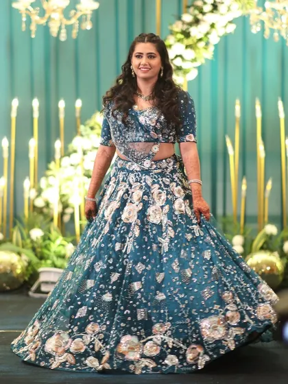 The bride looking radiant on her Sangeet night, posing against the beautifully lit floral stage we designed.