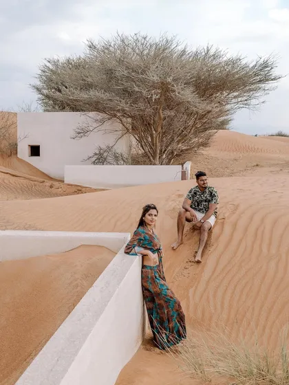 A destination pre-wedding shoot in the stunning Dubai desert. The unique architecture half-buried in sand creates a surreal and beautiful setting for this couple's portrait, showcasing how exotic locations can elevate a photoshoot.