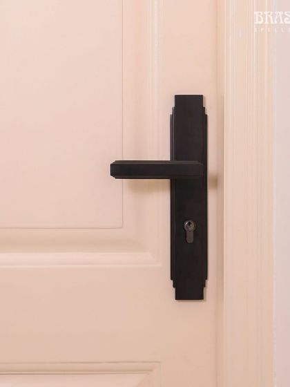 The Natali Lever Handle in a Jet Black finish, installed in a modern Juhu residence. Its design is defined by the clean, stepped detailing of Art Deco, creating a bold, geometric statement against the clean white door.