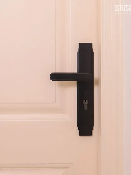 The Natali Lever Handle in a Jet Black finish, installed in a modern Juhu residence. Its design is defined by the clean, stepped detailing of Art Deco, creating a bold, geometric statement against the clean white door.