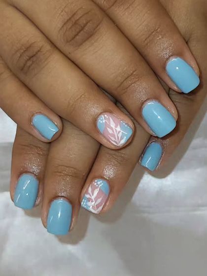 Elegant nails with minimal nail art. A beautiful pastel blue polish on short, natural nails with a simple leaf design on the ring finger.