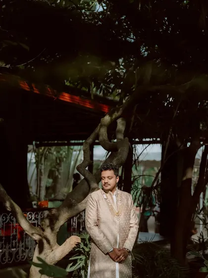 The groom, waiting for his bride, stands in the garden, a picture of calm and anticipation.