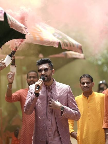 Leading the celebration with a mic in hand and color bombs in the air. This is how I ensure every wedding function is a vibrant, high-energy affair.