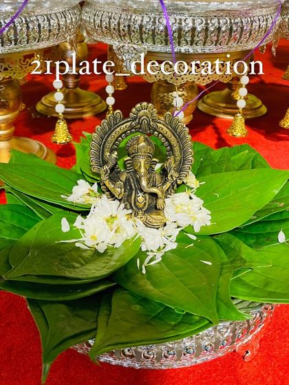 A close-up of a beautiful brass Ganesha idol placed on a bed of fresh betel leaves and flowers. This is a classic element I use in my plate arrangements for an auspicious start.