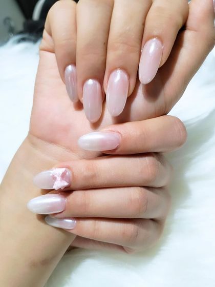 A soft and ethereal look with long, almond-shaped nails in a pearlescent pink, accented with a delicate 3D butterfly.