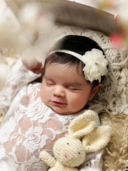 A close-up of a sleeping newborn girl holding a tiny knitted bunny. Props like these add a touch of sweetness to the portraits.