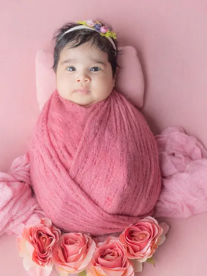 Wrapped in pink and crowned with blooms, our little flower has arrived.