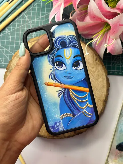 A finished hand-painted phone cover featuring a beautiful portrait of Krishna. The details in the eyes and the flute are carefully painted to bring a sense of peace and devotion to this custom accessory.
