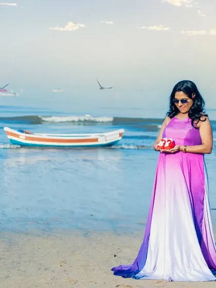 A moment of quiet reflection for the mom-to-be on the beach. She's holding a pair of tiny red shoes, dreaming of the little one to come.
