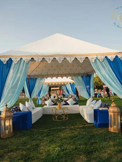 A luxurious tented seating area, draped in shades of blue, providing a comfortable and stylish space for guests to relax.