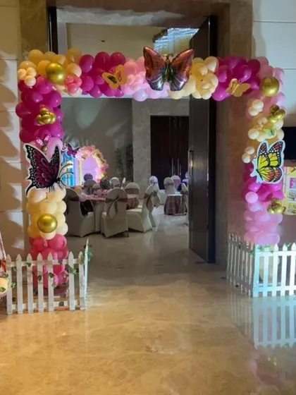 A beautiful butterfly-themed entrance arch in shades of pink and yellow, creating a whimsical welcome for a birthday party.