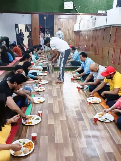 A community meal (bhandara) where students sit together in lines, sharing food in a traditional and communal way.