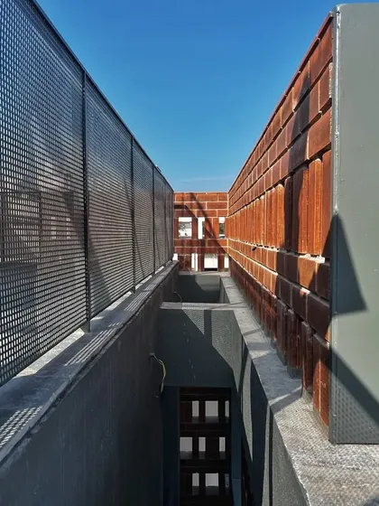 An on-site view showing the combination of perforated screen, brick, and concrete. This layering of materials creates a rich and detailed facade.