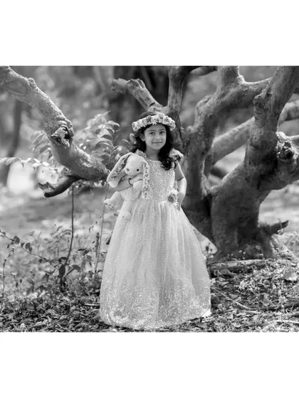 A wide shot of Brishka in her gown, rendered in black and white. This version emphasizes the contrast between her bright dress and the natural, leafy surroundings.