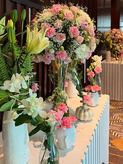 A closer look at the floral arrangements for a Roka ceremony. We used a mix of pink roses, white lilies, and carnations in various vases to create a textured and abundant floral display.