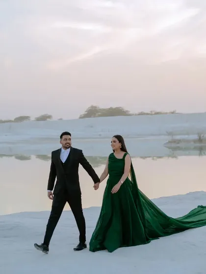 A candid walking shot along the water's edge at sunset. The warm light and the couple's relaxed interaction make this a beautiful and natural pre-wedding photograph.
