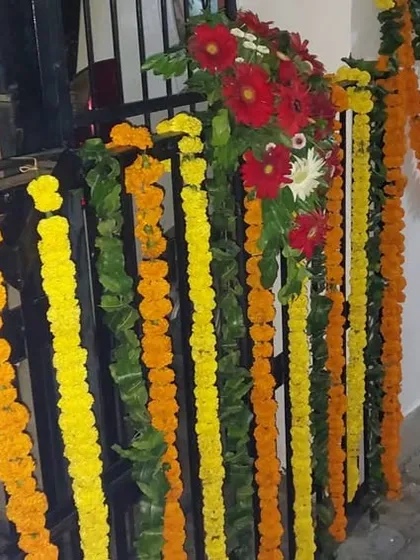 A close-up of the gate and wall decoration for a home wedding. We use a combination of marigold strings and small bouquets of mixed flowers to adorn railings and walls.