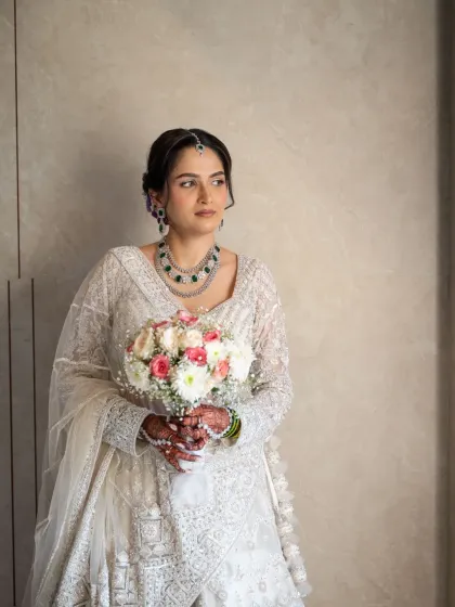 An elegant portrait of an Indian bride holding her bouquet. The soft, natural light from the window creates a timeless and classic look.