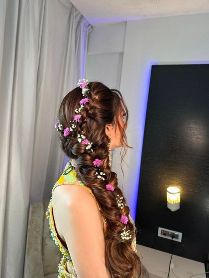 A side view of a messy braid adorned with delicate purple flowers and baby's breath, creating a soft and romantic hairstyle.