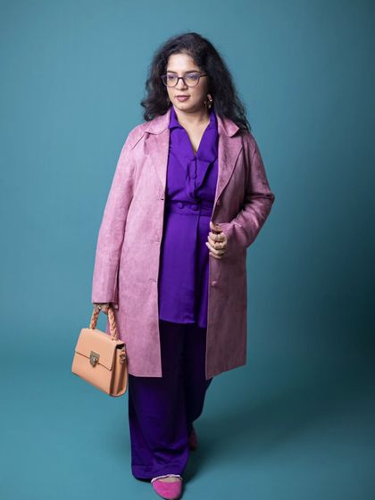 Another angle of this powerful color-blocking look. Notice how the structure of the pink coat complements the flow of the purple trousers, creating a balanced and visually interesting silhouette that commands attention.