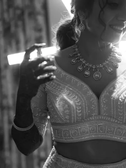 A close-up black and white shot focusing on the intricate jewelry and the bride's happy smile.