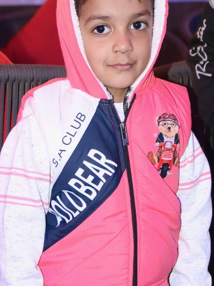 A cool and casual portrait of a young boy in a stylish hooded vest.