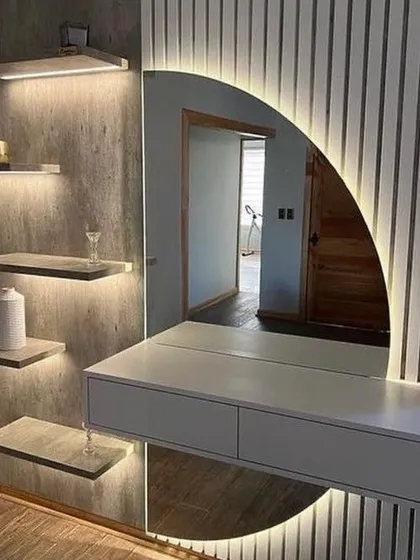 Our work goes beyond just wardrobes. We design and build integrated furniture like this stunning dresser and display unit. It features a backlit circular mirror, floating drawers, and illuminated shelves, creating a functional and artistic focal point in the room.