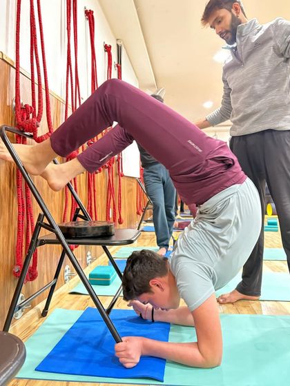 Here, I am observing and ready to assist as the student practices a supported forearm stand, ensuring he feels safe to explore his limits.