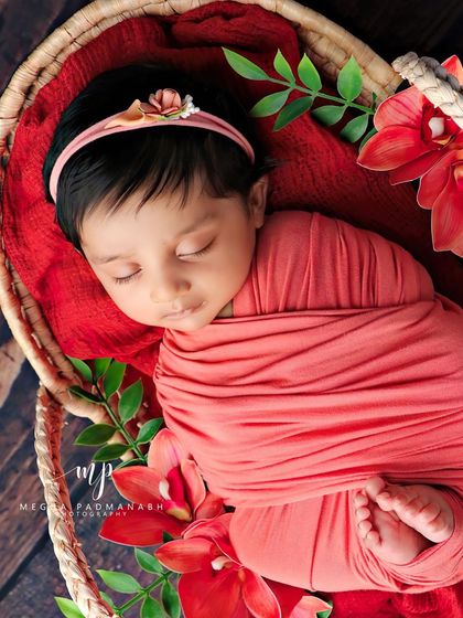 A close-up of the baby sleeping, wearing a delicate floral headband.