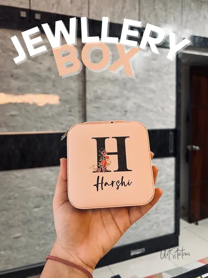 This personalized jewellery box is perfect for keeping your accessories organized. It features a custom initial "H" with a floral design and the name "Harshi" printed below, all on a lovely pale pink travel case.