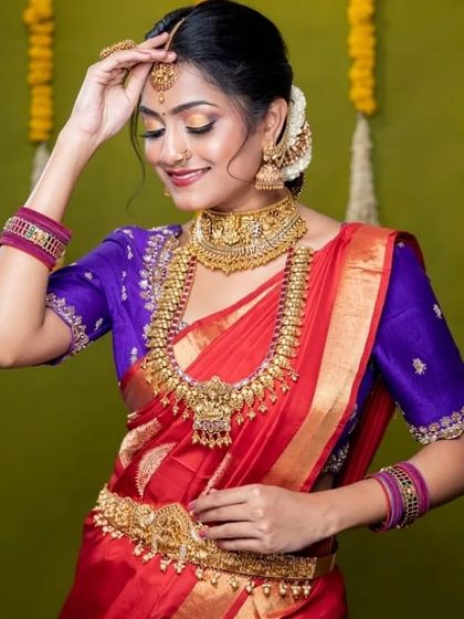 A beautiful shot of a model wearing a traditional temple jewellery set with a red and purple Kanjeevaram saree.