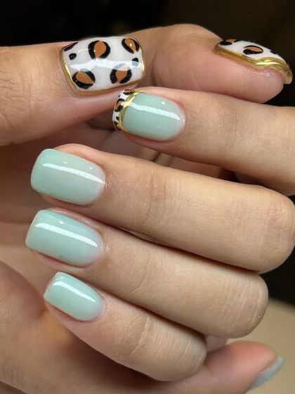 A playful and chic nail art design. This set combines a soft mint green with accent nails featuring a gold-rimmed leopard print for a fun and stylish contrast.