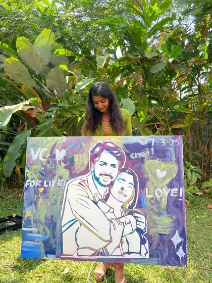 Holding up the finished couple's portrait. The abstract, colorful background was filled in by guests, making it a truly collaborative piece.