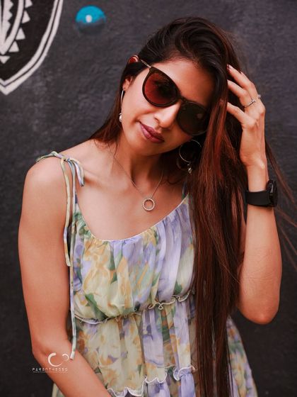 A chic and stylish portrait with sunglasses. The hand in her hair adds a touch of candid movement, making the pose feel natural and unforced.