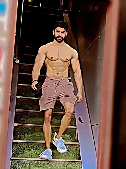 A full body shot walking down the stairs in the gym, showing overall conditioning and leg development.