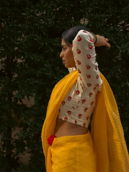 A profile view capturing the subject adjusting her hair against a dark green background. This highlights the details of the blouse and the elegant lines of the pose.