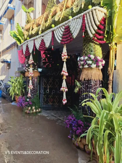 Another perspective of the grand home entrance decor, capturing the lush greenery and the vibrant colours of the flowers against the building.