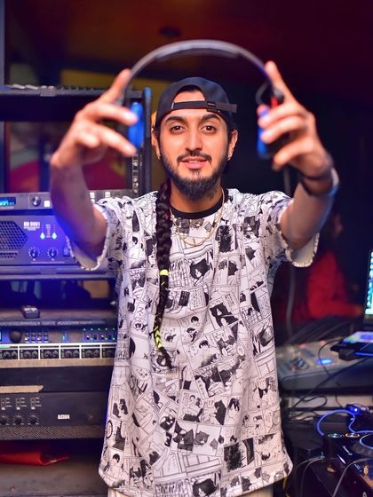 Holding up my headphones, ready for the next transition. A good DJ is always listening and preparing.