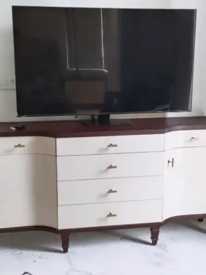 A custom TV unit with a unique curved design, combining a dark wood finish with off-white doors and drawers. This piece is tailored to provide ample storage while adding a distinctive stylistic element.