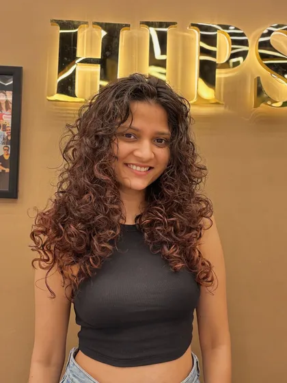 A smiling client, confident and happy with her curly hair makeover. The style is full of life and personality.