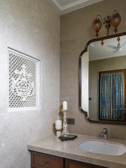 In this Hyderabad bathroom, a handcrafted lattice or 'jaali' panel elegantly divides the shower and dry areas. This element, inspired by traditional Indian architecture, adds a beautiful, handcrafted touch while maintaining a sense of openness.
