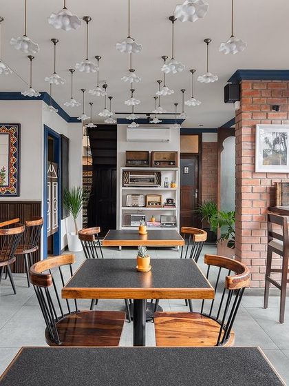 The dining area एट Klaa Kitchen, a slice of Goa in Bangalore. The space is filled with natural light, exposed brick, and custom art, creating a warm and welcoming "Goan home" atmosphere.