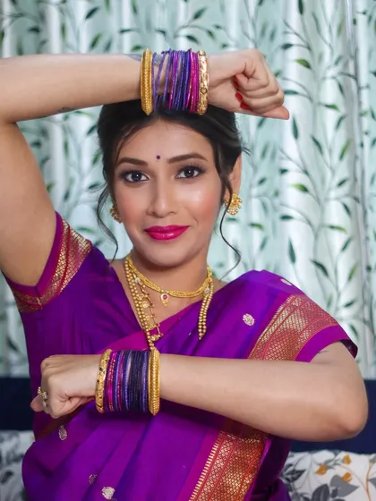 A playful and graceful pose that shows off the vibrant colors of the saree and the flawless makeup.